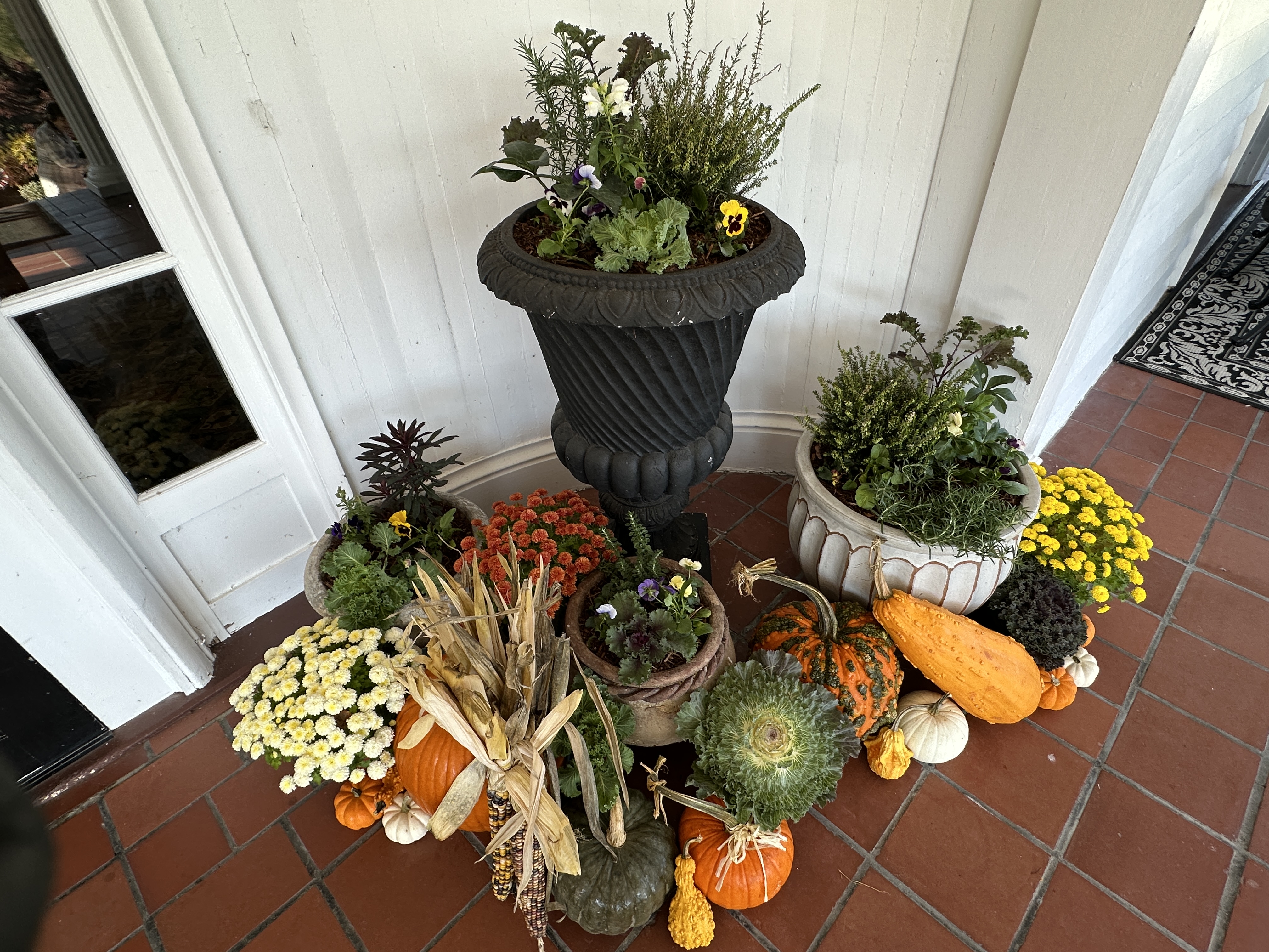 Three focal planters surrounded by pumpkins against a white entry